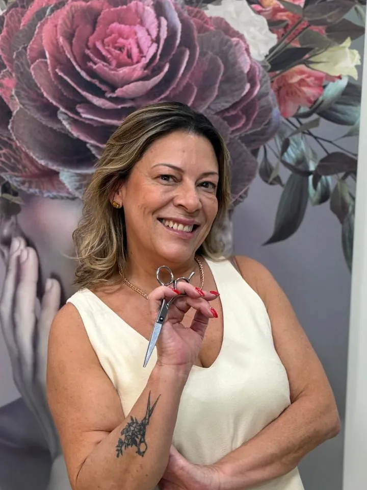 Néia, à frente da Nuovi Capelli, sorrindo com a tesoura na mão
